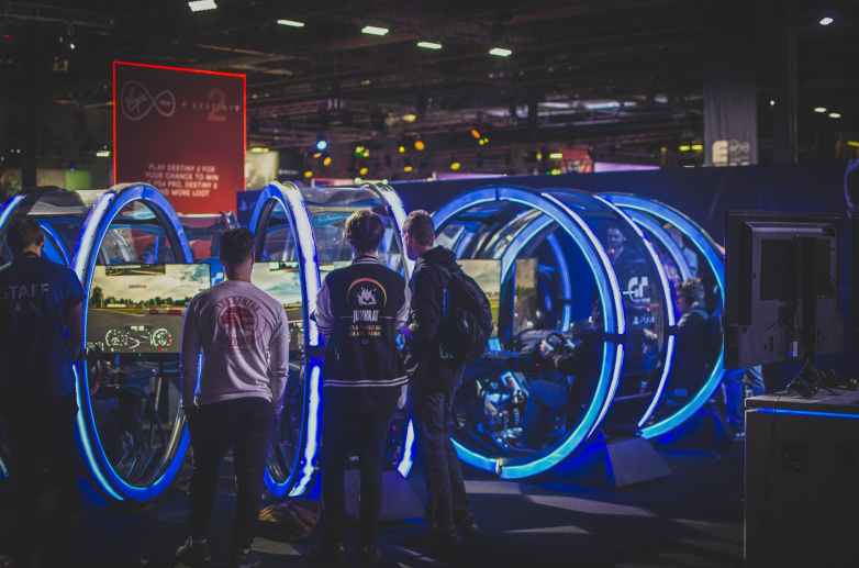 three men standing in front of racing arcade machines